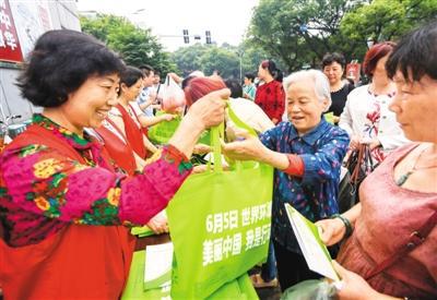 6月4日,江西省新余市渝水区城北街道办的志愿者在恭惠农贸市场门口向群众免费发放环保袋。周 亮摄(人民视觉)